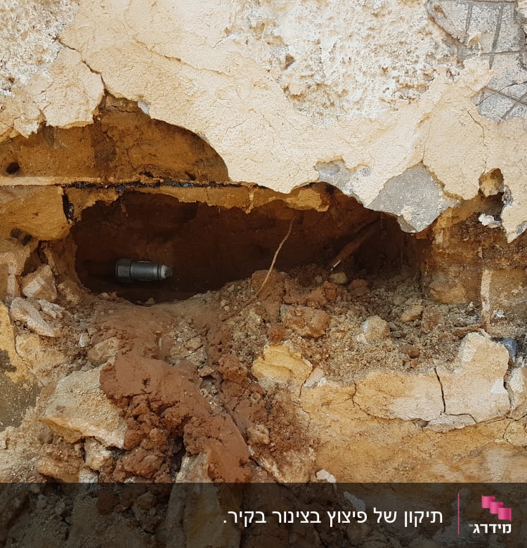 צינור מתכת חשוף בקיר שבור עם אדמה